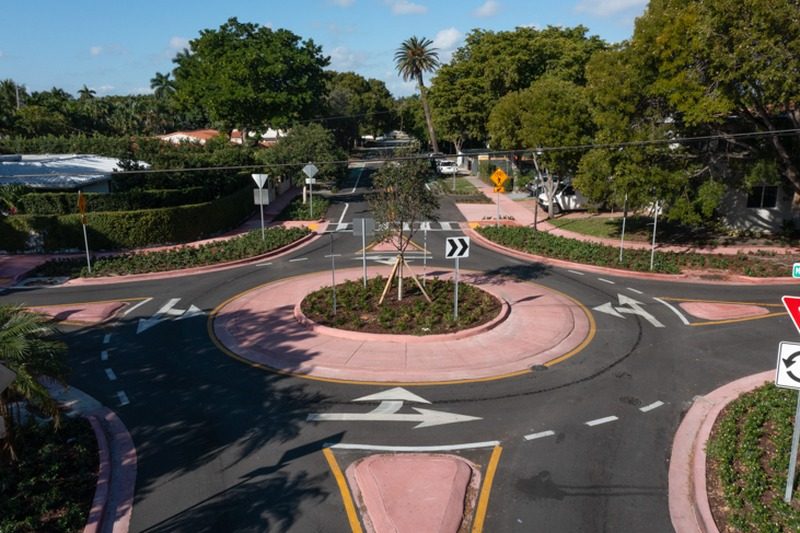 City rendering of a landscaped traffic circle with pink curbs at a tree-lined residential intersection