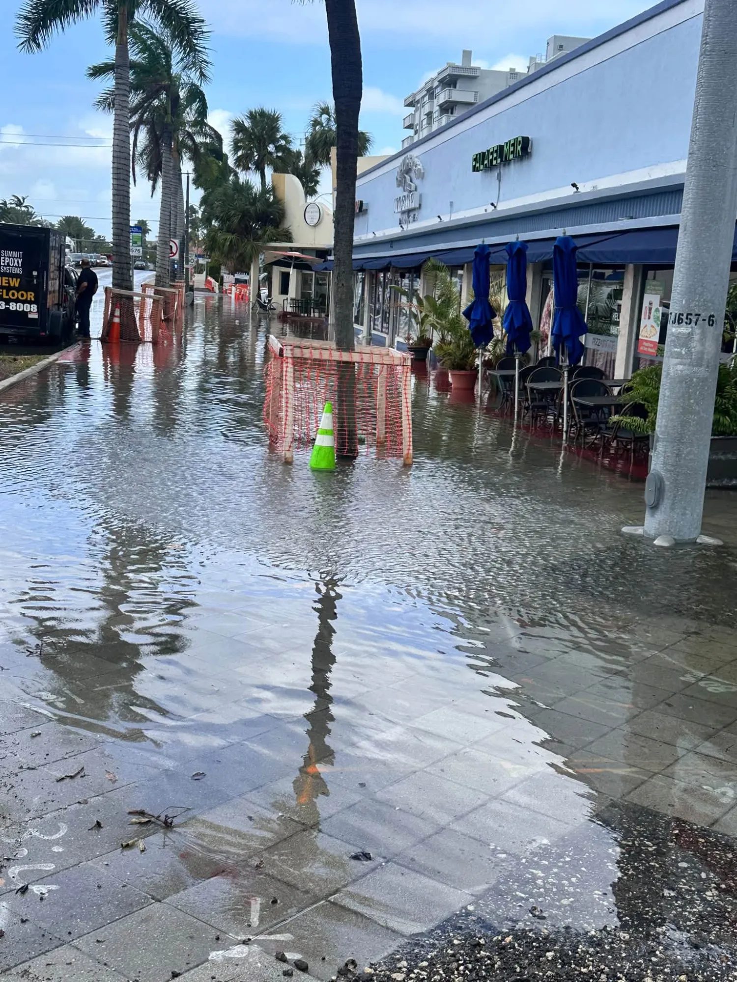 Seawater covering the sidewalk and outdoor tables outside storefronts on 71st Street in North Beach