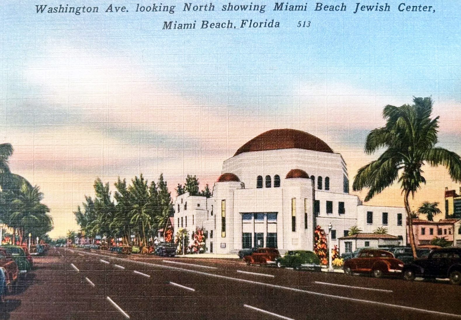 Postcard view of Washington Avenue in Miami Beach looking north, with shops and cars lining the street